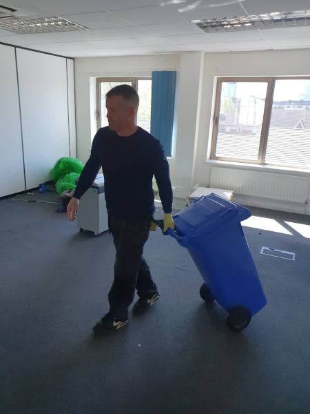 Person Clearing Office with Large Bin